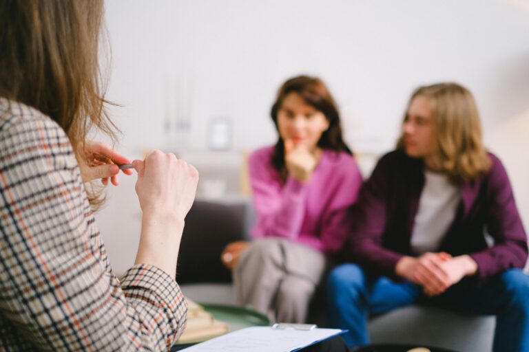 Why does therapy sometimes stall? A calm therapy office with three people in conversation, representing thoughtful, structured mental health support.