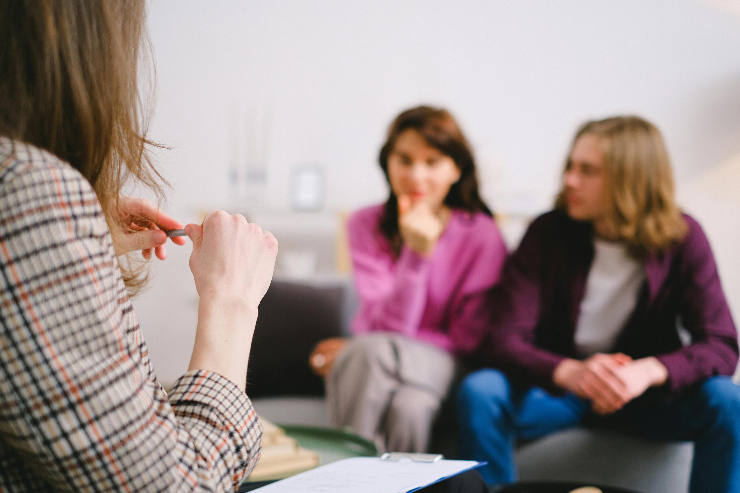 Why does therapy sometimes stall? A calm therapy office with three people in conversation, representing thoughtful, structured mental health support.