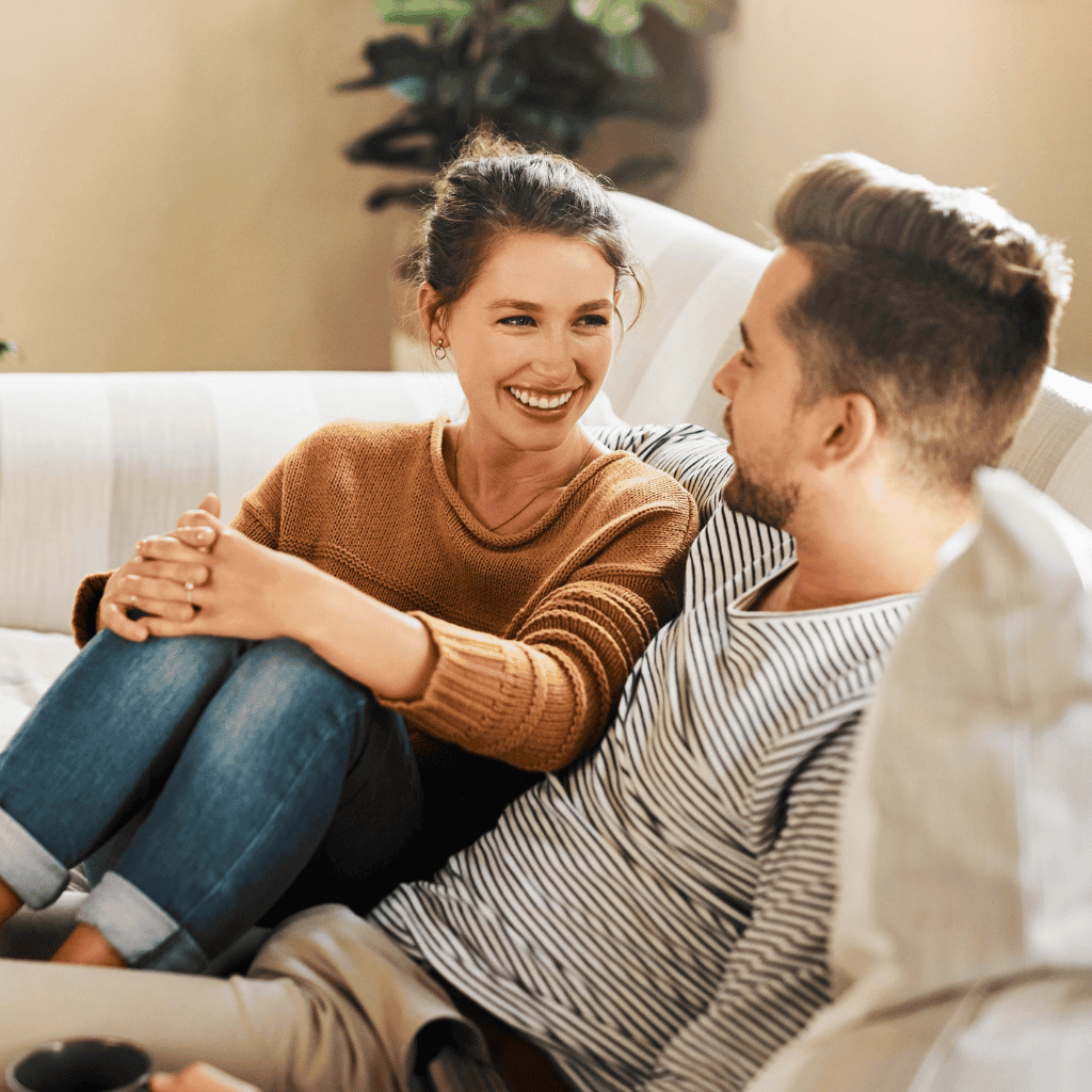 Couple sitting on a couch smiling at each other